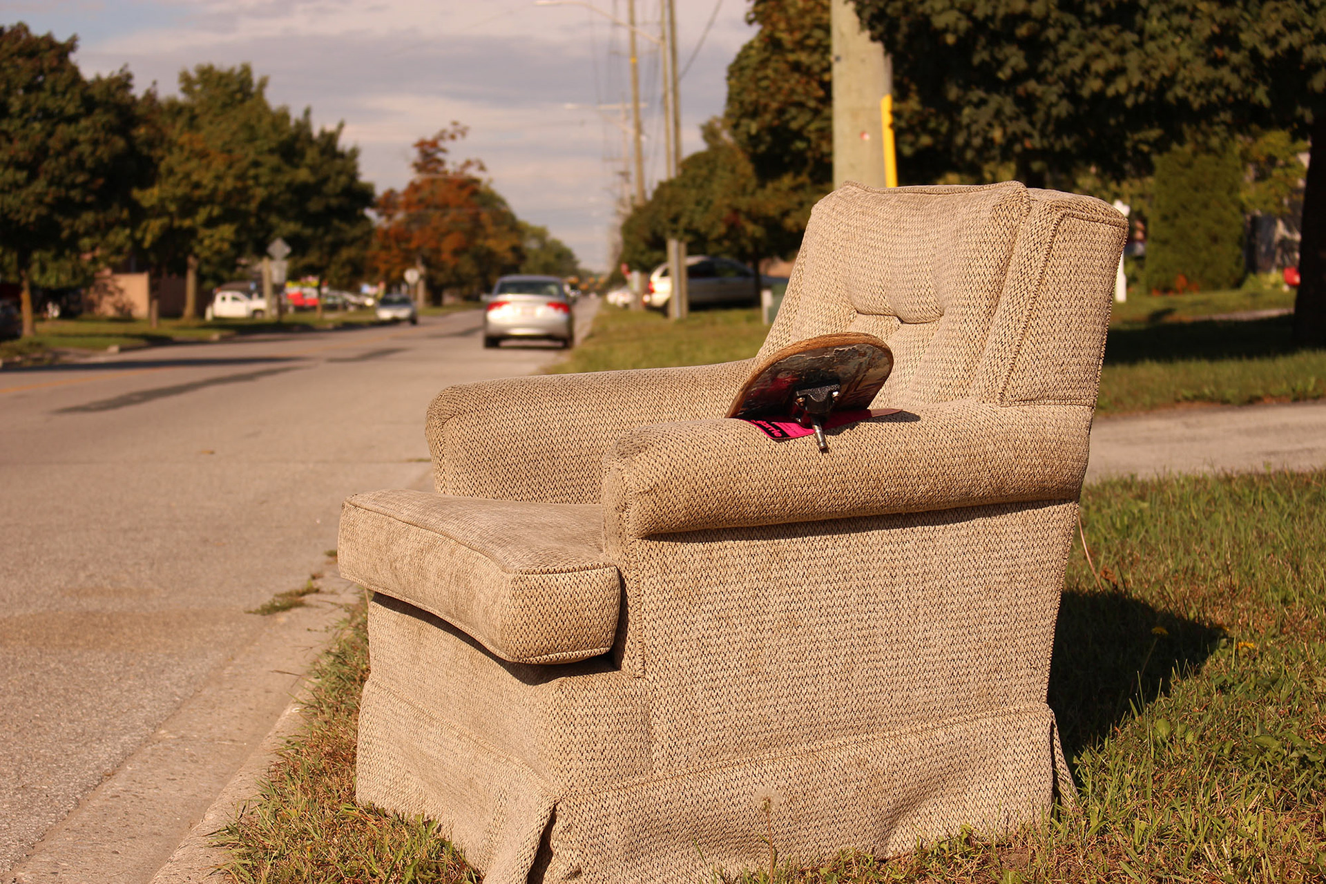 brown upholstered chair with skate board on side of the street